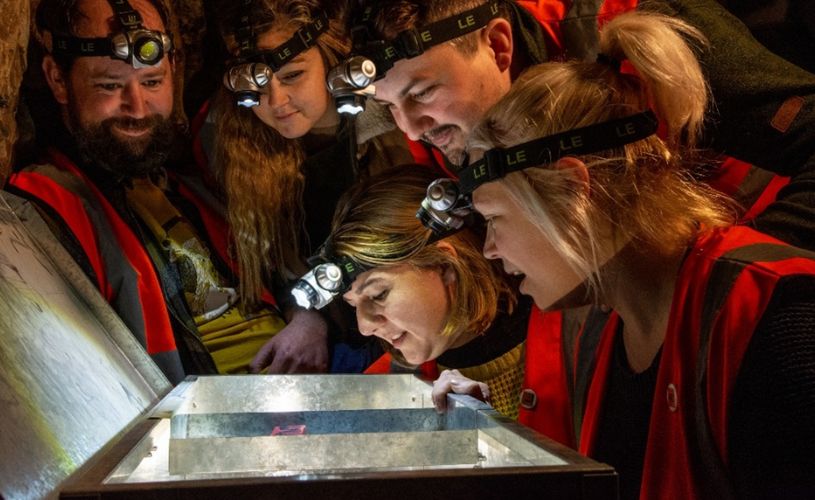 A group of people wearing head torches looking into a box
